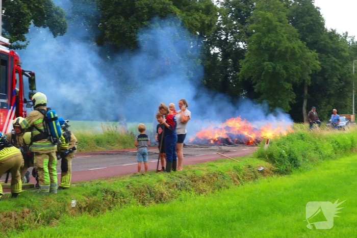 Brandweer blust brandend stro op aanhanger