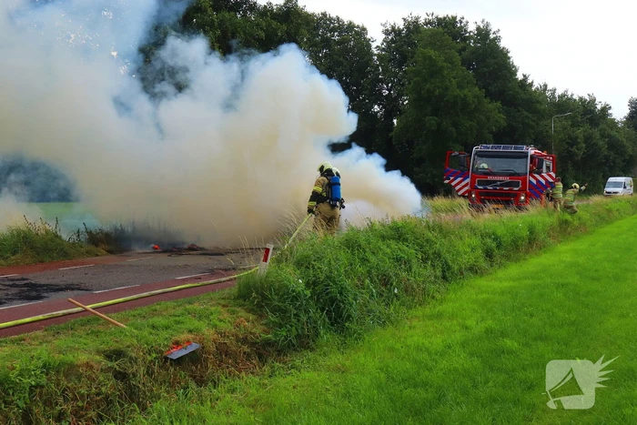Brandweer blust brandend stro op aanhanger