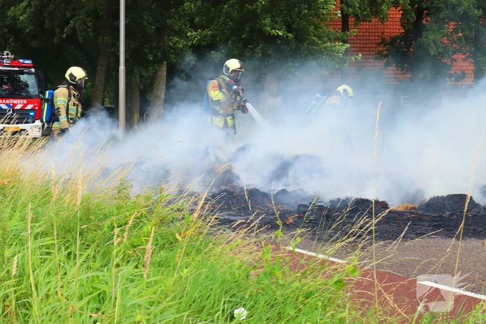 Brandweer blust brandend stro op aanhanger