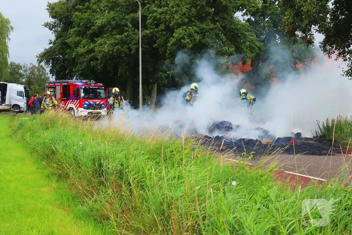 Brandweer blust brandend stro op aanhanger