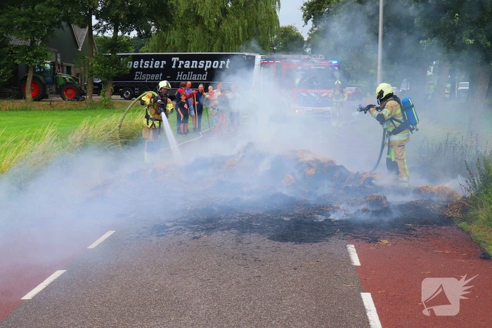 Brandweer blust brandend stro op aanhanger
