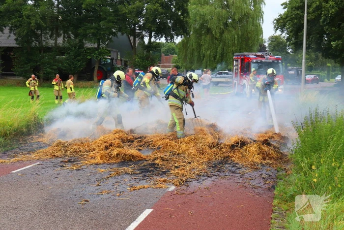 Brandweer blust brandend stro op aanhanger