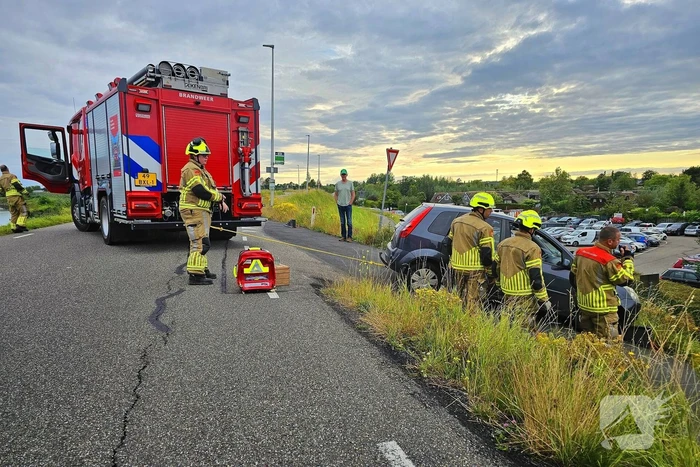 Brandweer trekt auto terug de dijk op