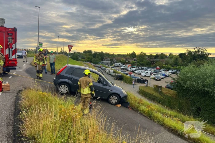 Brandweer trekt auto terug de dijk op