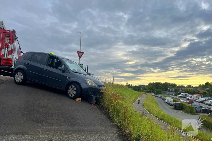 Brandweer trekt auto terug de dijk op