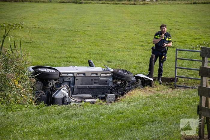 Omstanders halen automobilist uit te water geraakte auto