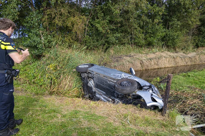 Omstanders halen automobilist uit te water geraakte auto