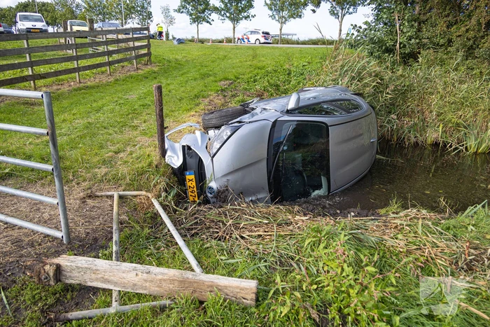 Omstanders halen automobilist uit te water geraakte auto