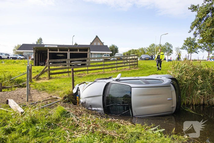 Omstanders halen automobilist uit te water geraakte auto