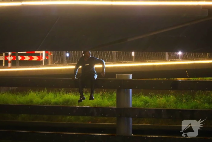 Persoon klimt op palen onder brug en word gebeten door politiehond