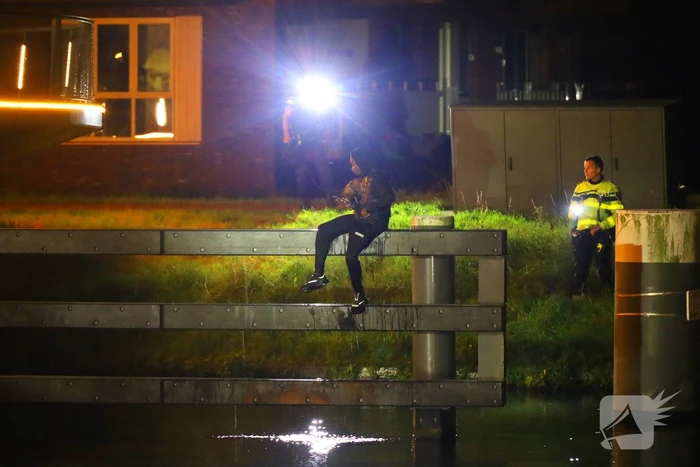 Persoon klimt op palen onder brug en word gebeten door politiehond