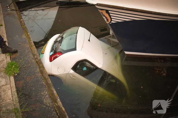 Auto rolt jachthaven in en gaat kopje onder