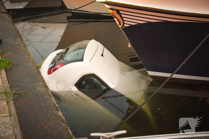 Auto rolt jachthaven in en gaat kopje onder
