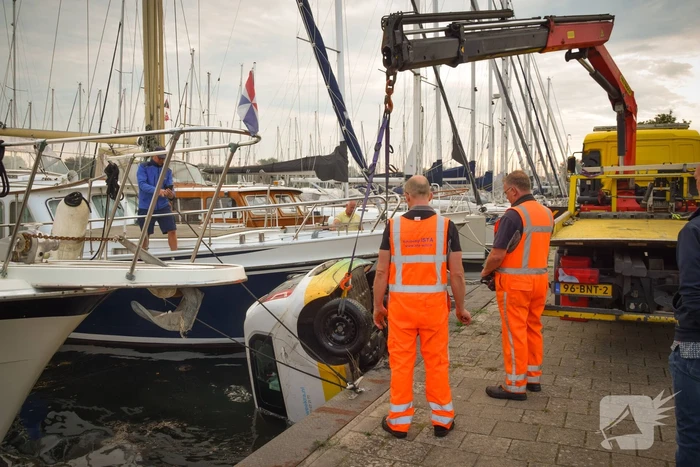 Auto rolt jachthaven in en gaat kopje onder