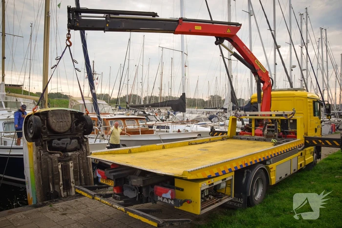Auto rolt jachthaven in en gaat kopje onder