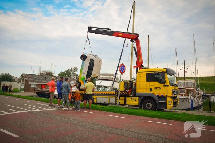 Auto rolt jachthaven in en gaat kopje onder