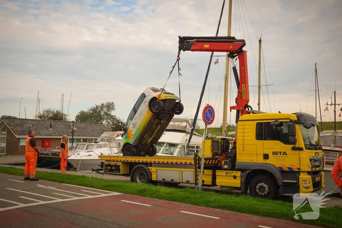 Auto rolt jachthaven in en gaat kopje onder
