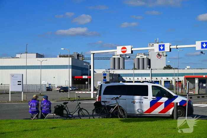 Demonstranten klimmen over hekken van zuivel fabrikant