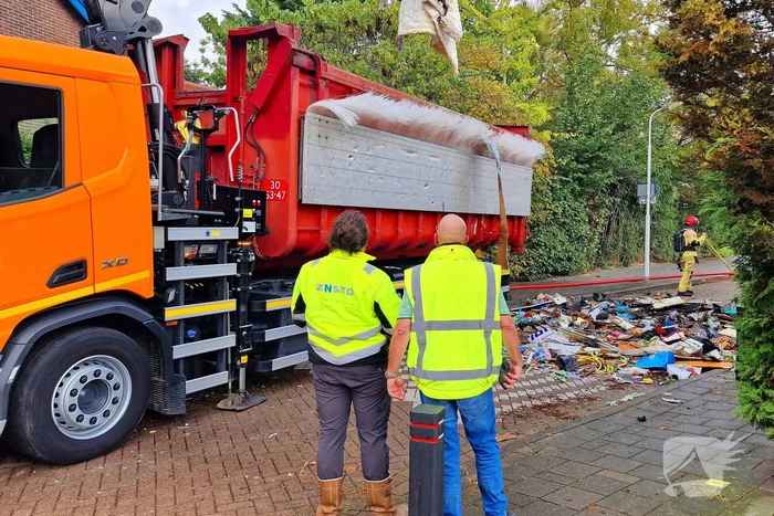 Containerwagen dumpt brandend afval op straat