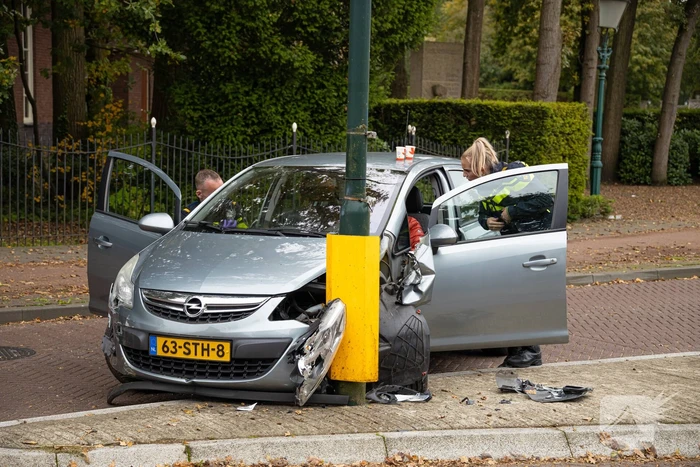 Automobilist ramt verkeersbord en lantaarnpaal