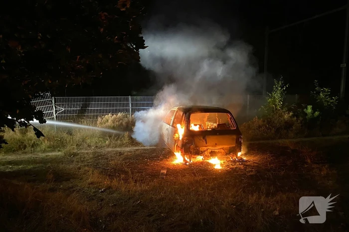 Brandweer blust brandende auto in bosgebied