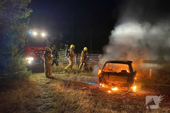 Brandweer blust brandende auto in bosgebied