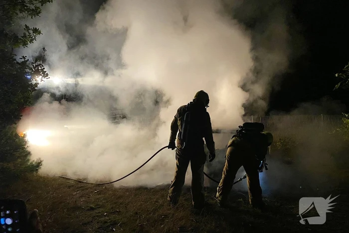 Brandweer blust brandende auto in bosgebied