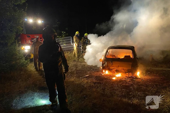 Brandweer blust brandende auto in bosgebied