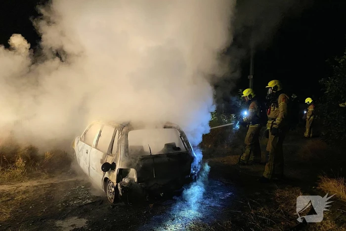 Brandweer blust brandende auto in bosgebied