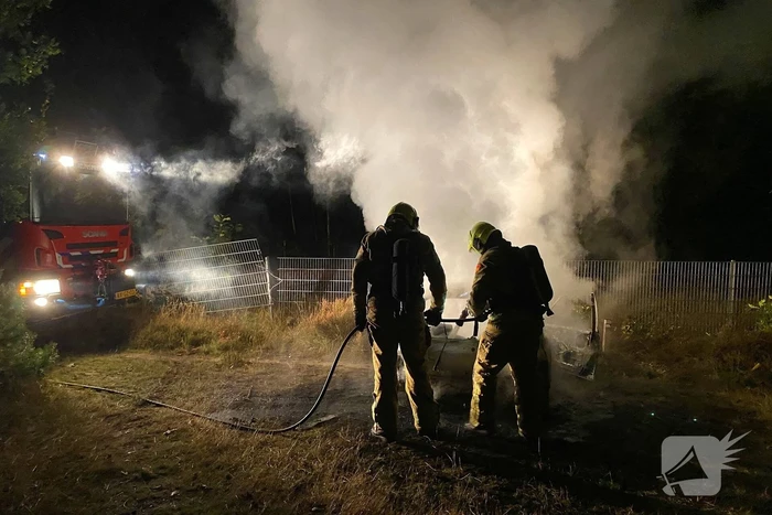 Brandweer blust brandende auto in bosgebied