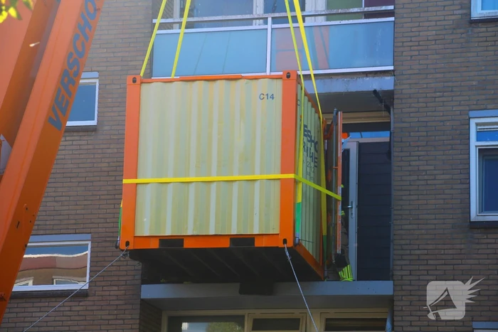 Persoon door hijskraan uit flatwoning getakeld