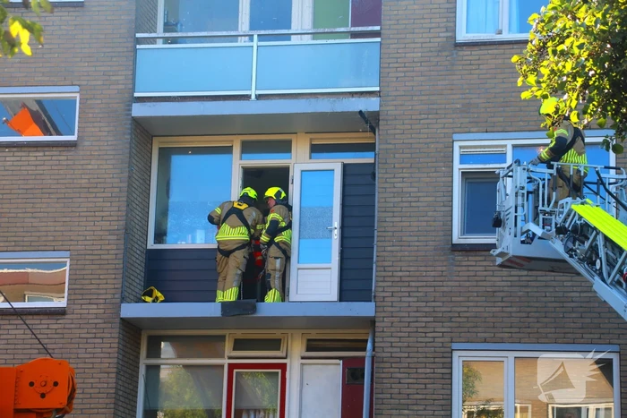 Persoon door hijskraan uit flatwoning getakeld
