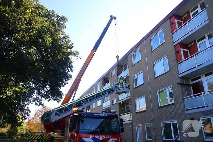 Persoon door hijskraan uit flatwoning getakeld