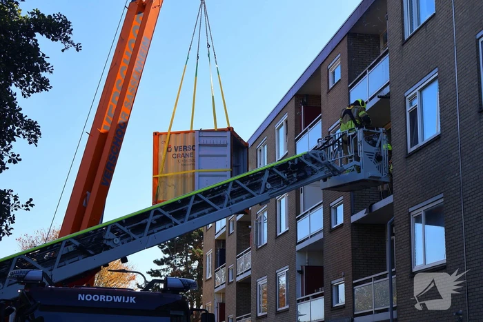 Persoon door hijskraan uit flatwoning getakeld
