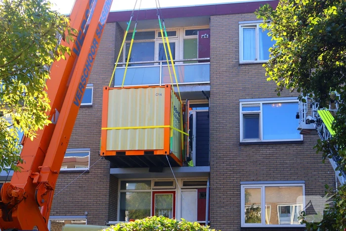 Persoon door hijskraan uit flatwoning getakeld