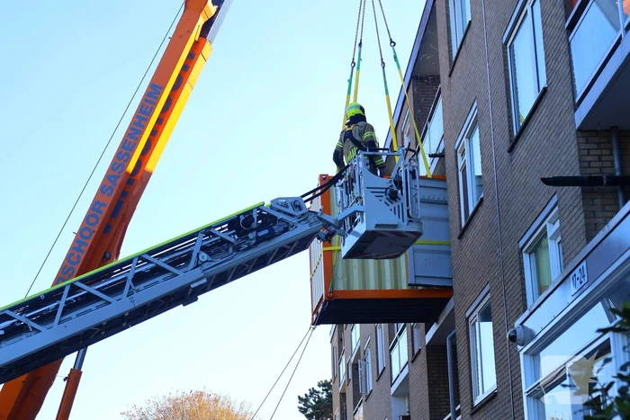 Persoon door hijskraan uit flatwoning getakeld