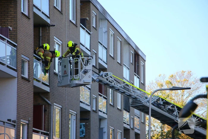 Persoon door hijskraan uit flatwoning getakeld