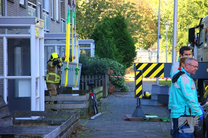 Persoon door hijskraan uit flatwoning getakeld