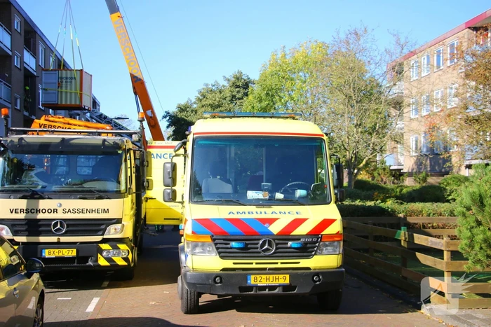 Persoon door hijskraan uit flatwoning getakeld