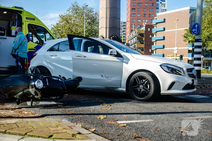 Scooter rijdt in zijkant van auto