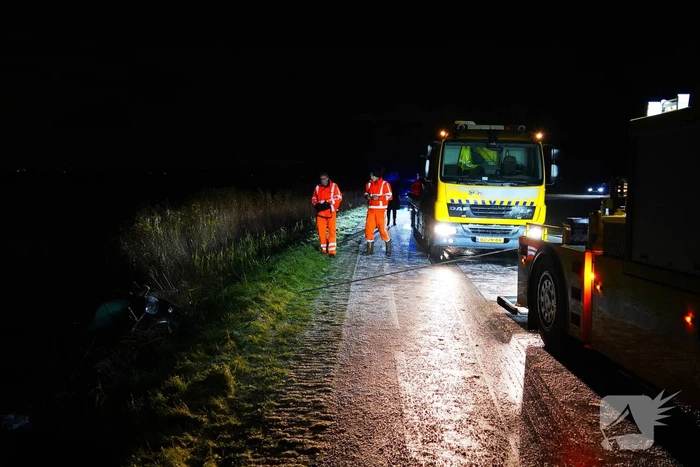 Twee auto's te water in bocht op gladde dijk