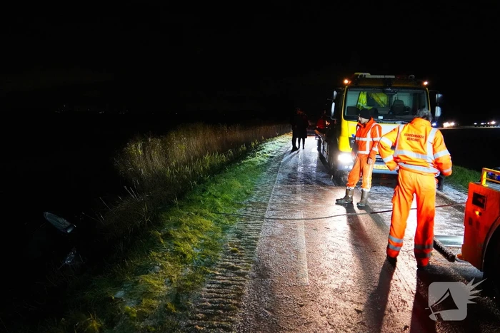 Twee auto's te water in bocht op gladde dijk