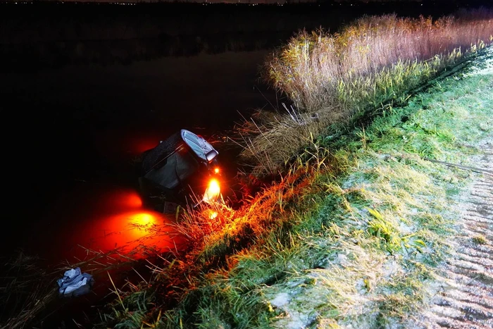 Twee auto's te water in bocht op gladde dijk
