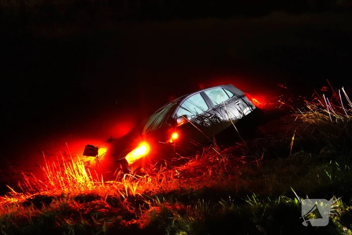 Twee auto's te water in bocht op gladde dijk