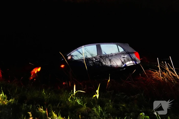 Twee auto's te water in bocht op gladde dijk