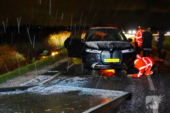 Twee auto's te water in bocht op gladde dijk
