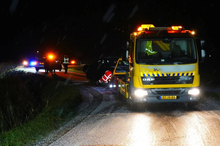 Twee auto's te water in bocht op gladde dijk
