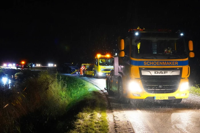 Twee auto's te water in bocht op gladde dijk