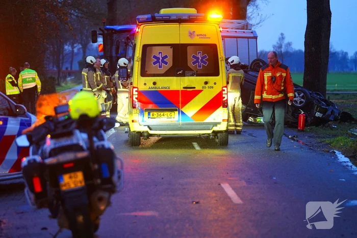 Auto op de kop na botsing met trekker en boom
