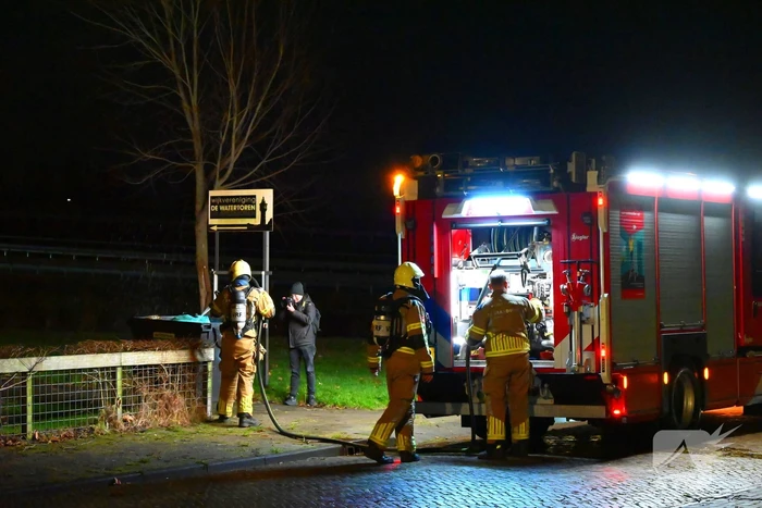 Brandweer blust brand in vuilcontainer